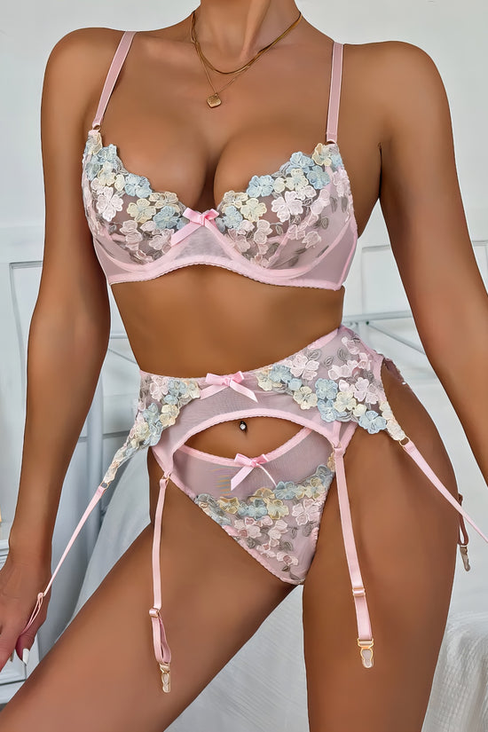 Woman wearing a white mesh 2-piece lingerie set with pink embroidery, posing on a white background