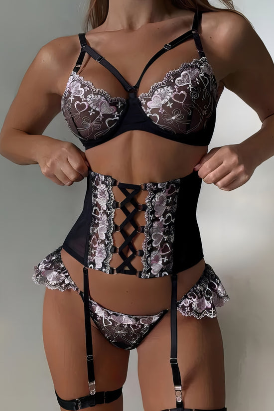 Woman wearing a black mesh 2-piece lingerie set with pink embroidery, posing on a white background