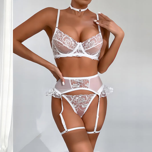 Woman wearing a luxury white mesh 3-piece lingerie set with pink floral embroidery, including underwire bra, garter belt, and matching thong