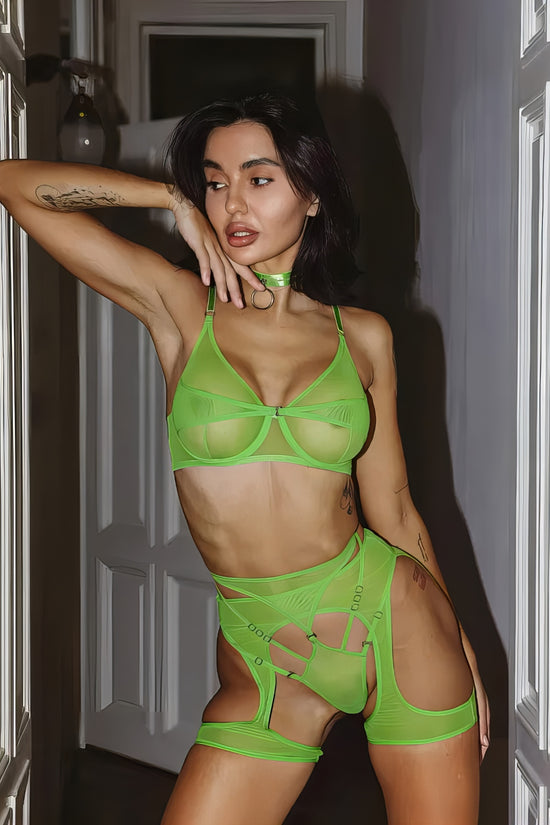 Woman wearing a luxury green mesh 3-piece lingerie set with embroidery, including underwire bra, garter belt, and matching thong