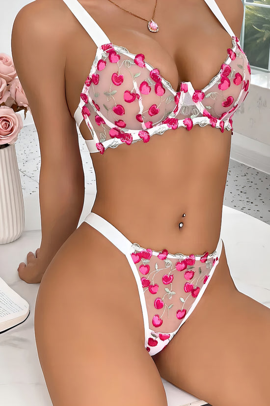 Woman wearing a white mesh 2-piece lingerie set with pink embroidery, posing on a white background