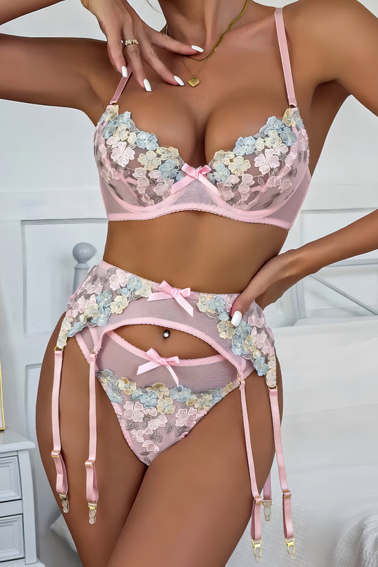 Woman wearing a white mesh 2-piece lingerie set with pink embroidery, posing on a white background