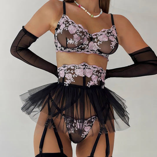 Woman wearing a black mesh 2-piece lingerie set with purple embroidery, posing on a white background
