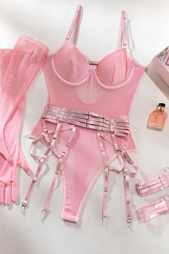 Woman wearing a luxury pink mesh 3-piece lingerie set with embroidery, including underwire bra, garter belt, and matching thong