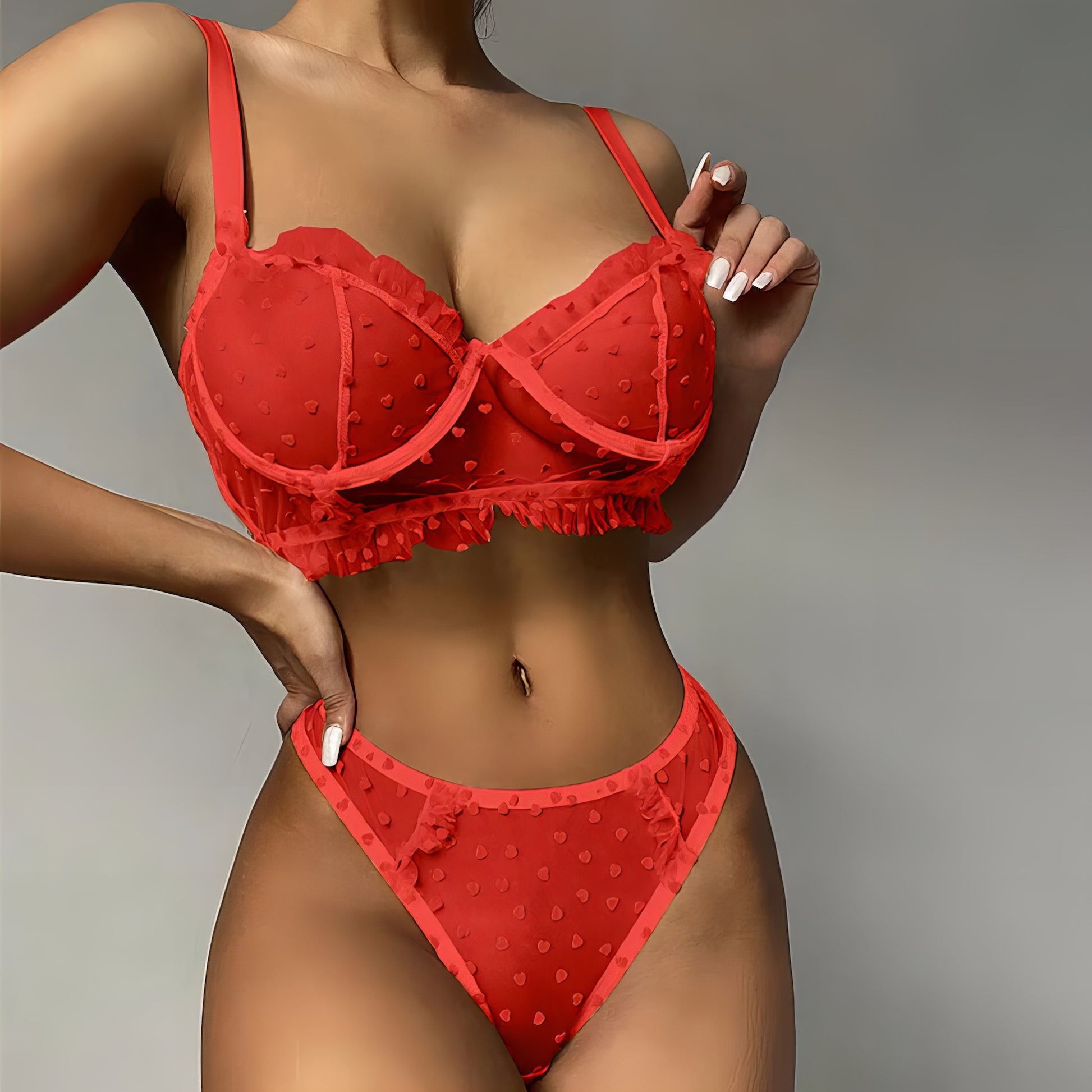 Woman wearing a red mesh 2-piece lingerie set with red embroidery, posing on a white background