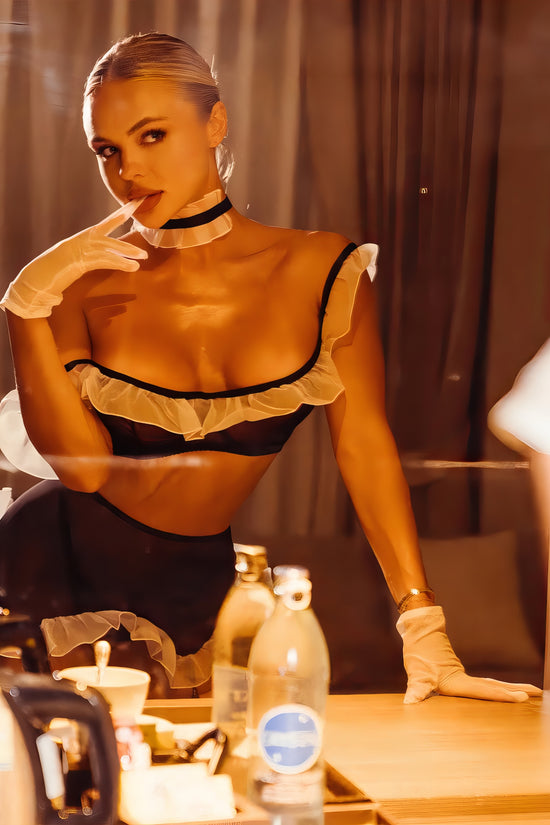 Woman wearing a luxur black and white mesh 3-piece lingerie set with pink floral embroidery, including underwire bra, garter belt, and matching thong
