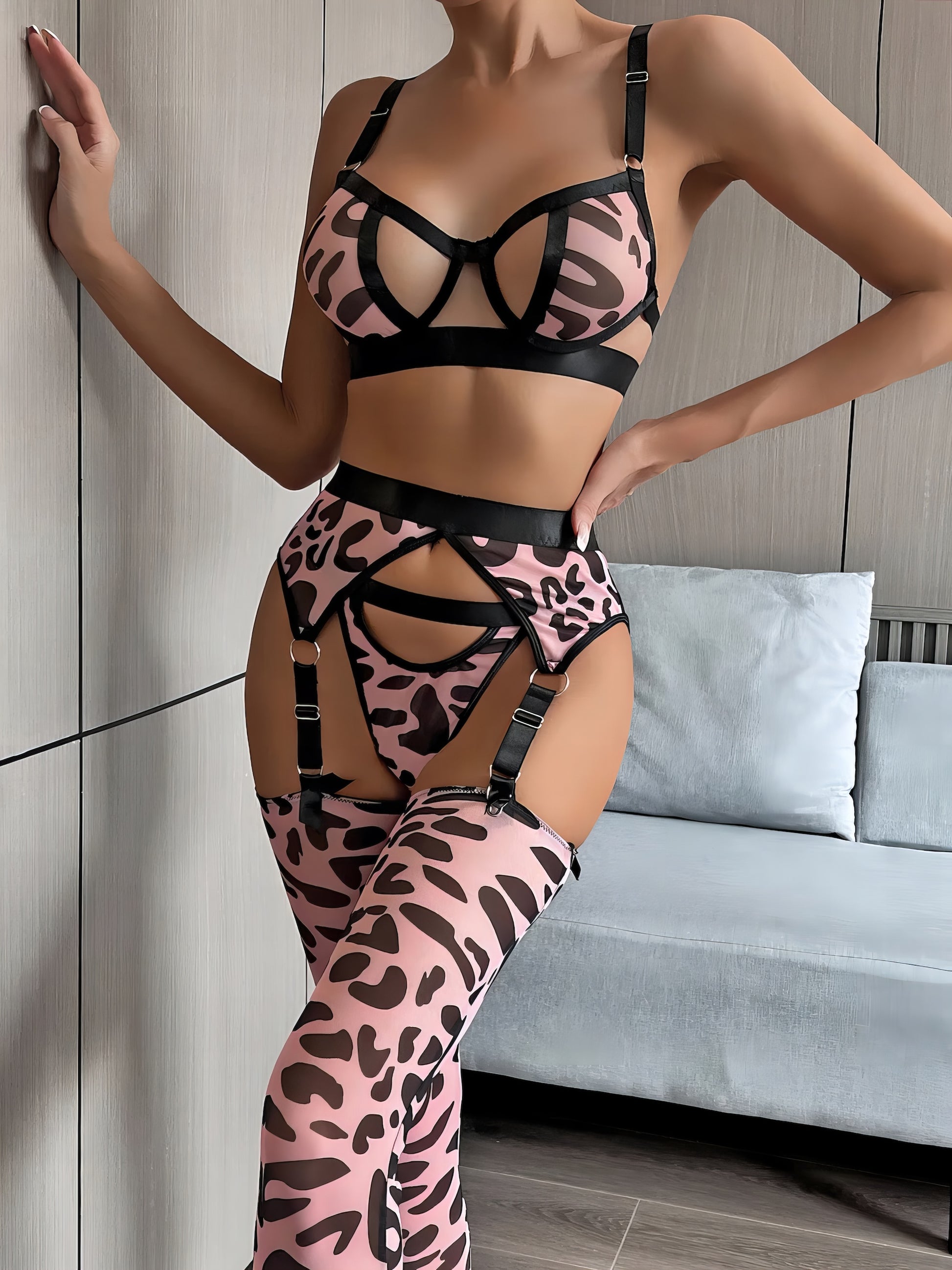 Woman wearing a luxury pink mesh 3-piece lingerie set with embroidery, including underwire bra, garter belt, and matching thong
