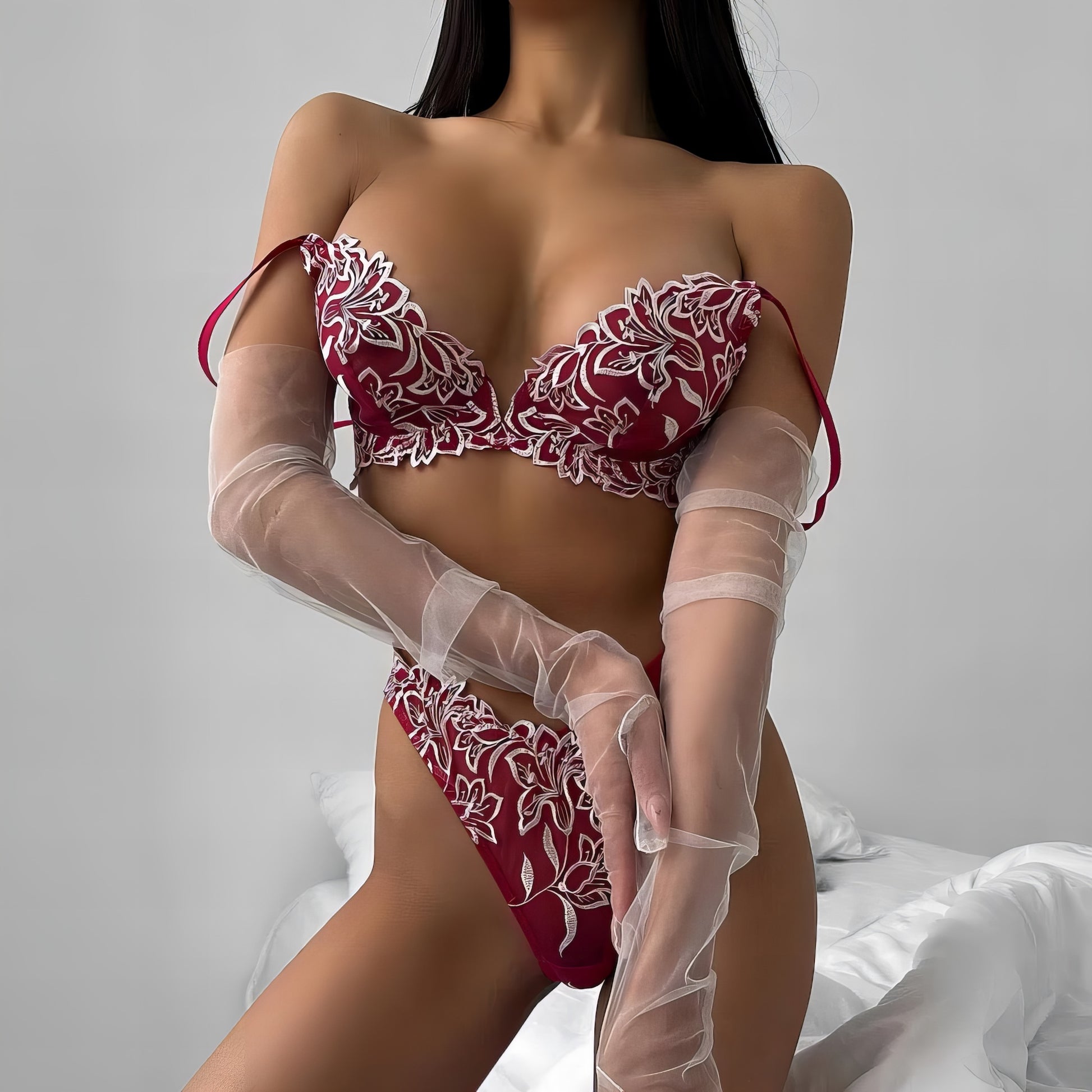 Woman wearing a red mesh 2-piece lingerie set with white embroidery, posing on a white background