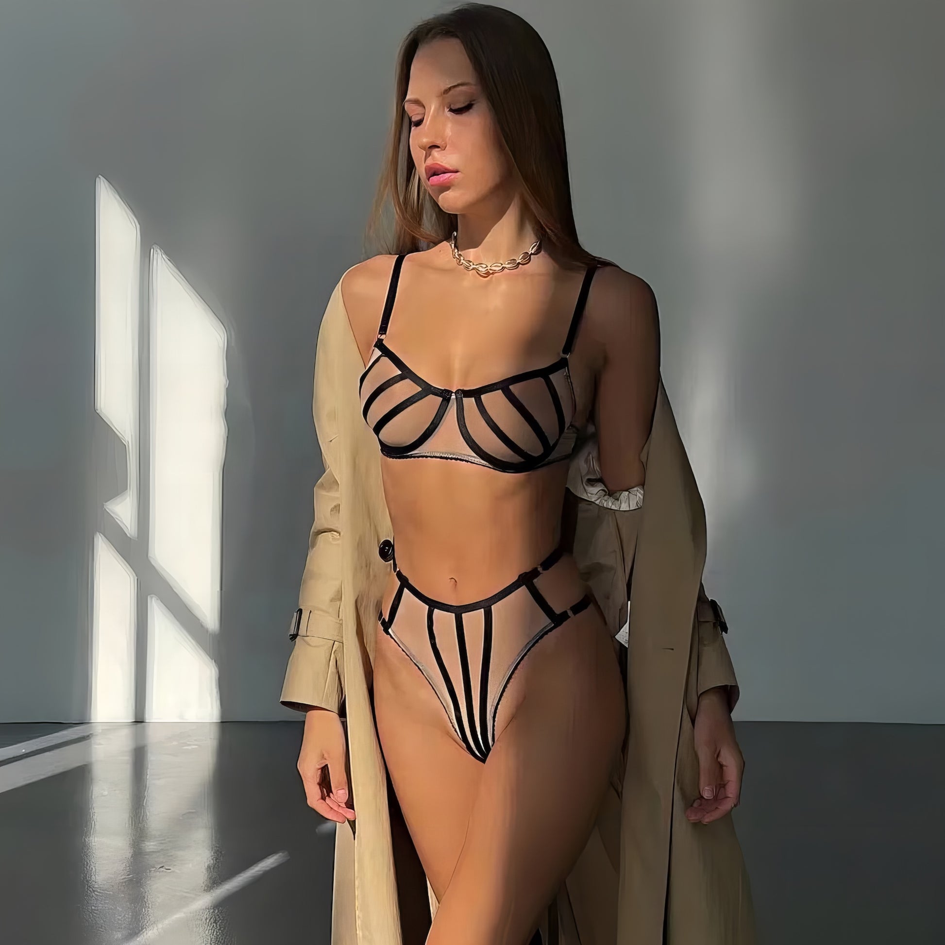 Woman wearing a beige mesh 2-piece lingerie set with embroidery, posing on a white background