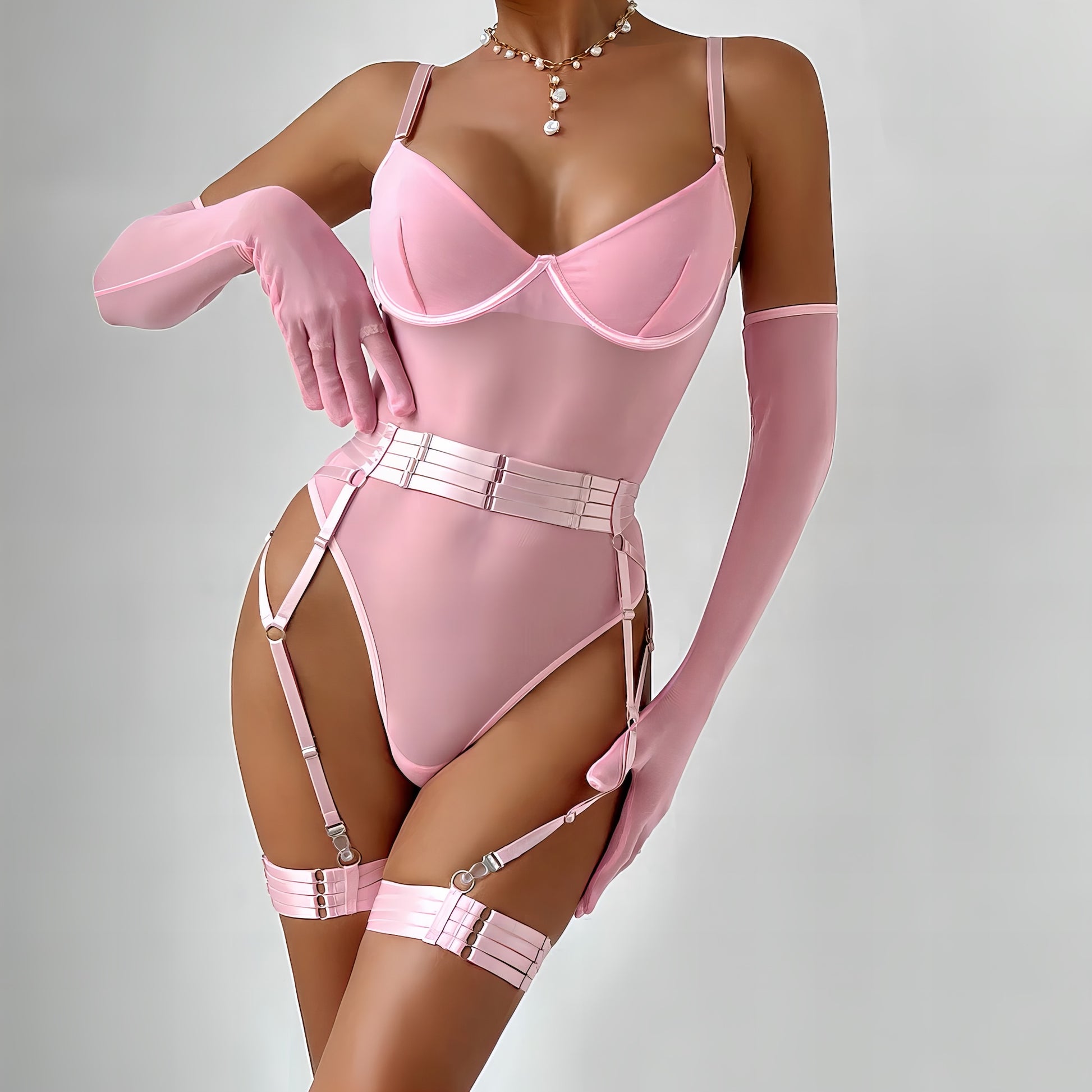 Woman wearing a luxury pink mesh 3-piece lingerie set with embroidery, including underwire bra, garter belt, and matching thong